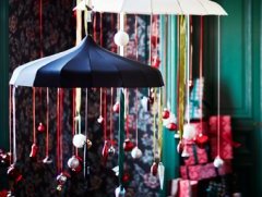 Два зонта, подвешенные к потолку и украшенные красными лентами и елочными игрушками белого, красного и серебряного цветов.