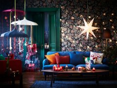 Украшенная гостиная с зажженными свечами на журнальном столике, гирлянда на стене и большая рождественская звезда.